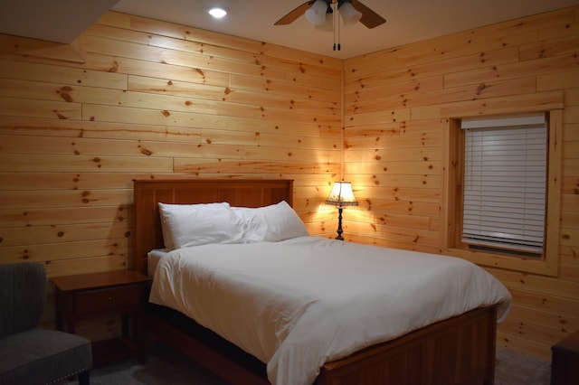 bedroom featuring ceiling fan and wood walls