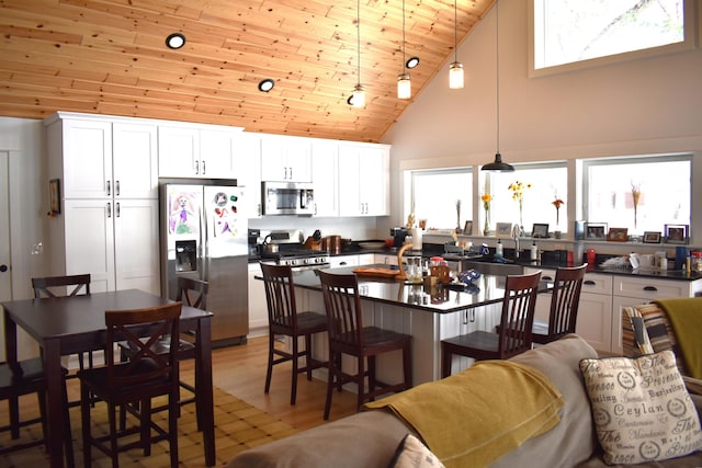 kitchen featuring pendant lighting, appliances with stainless steel finishes, a kitchen bar, and white cabinets