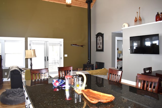 dining space with high vaulted ceiling, french doors, and a wood stove