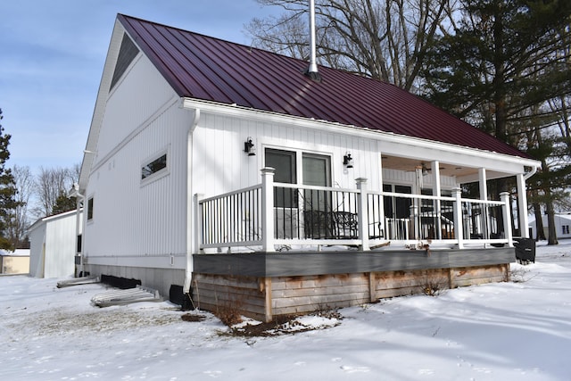 snow covered rear of property with a porch