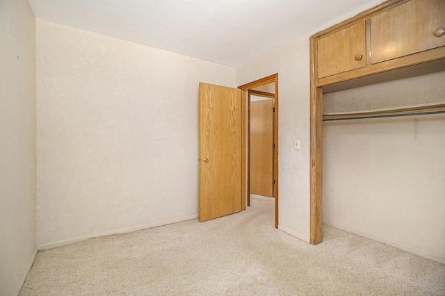 unfurnished bedroom with light carpet and a closet