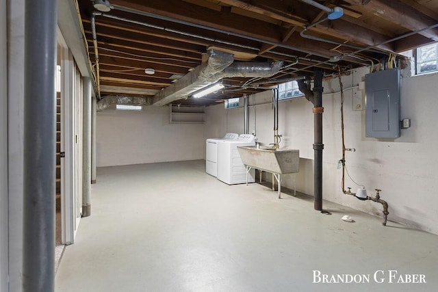 basement featuring washing machine and clothes dryer, electric panel, and sink