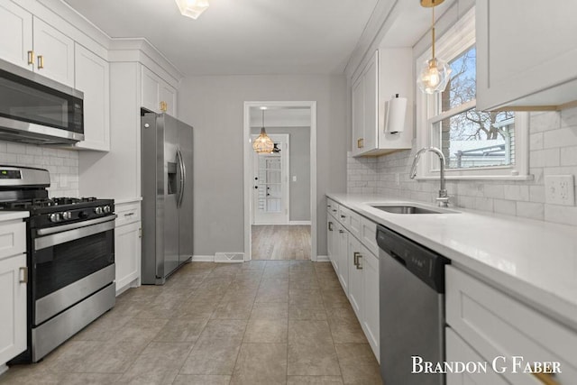 kitchen featuring white cabinetry, sink, decorative light fixtures, and stainless steel appliances