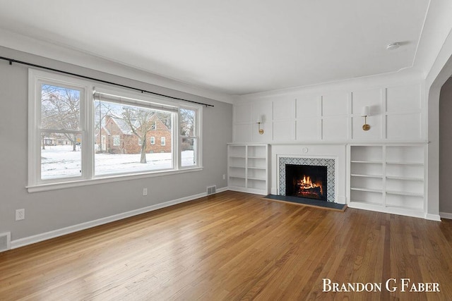 unfurnished living room with hardwood / wood-style flooring, a fireplace, and built in features