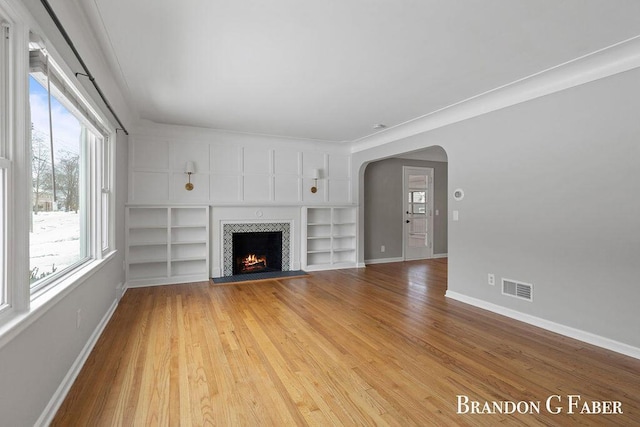 unfurnished living room featuring built in features and light wood-type flooring