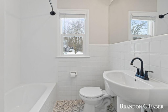 bathroom with tile patterned floors, plenty of natural light, toilet, and a bathing tub