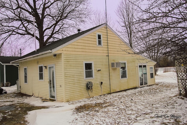 snow covered back of property with a wall unit AC