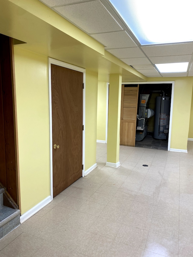 interior space featuring heating unit, a paneled ceiling, and water heater