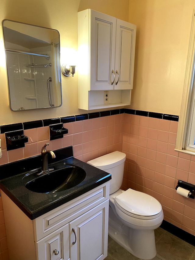 bathroom featuring walk in shower, tile patterned floors, toilet, tile walls, and vanity