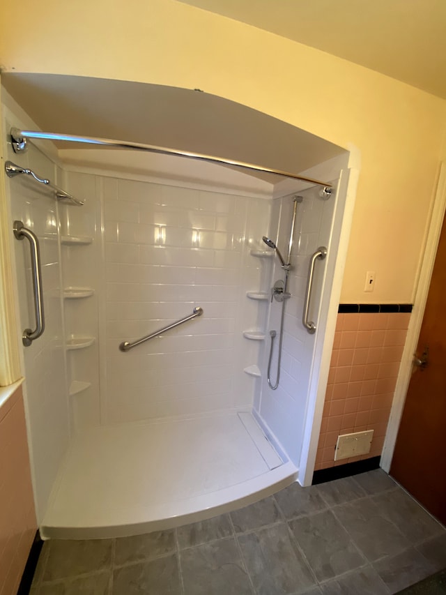 bathroom featuring tile patterned flooring, a tile shower, and tile walls