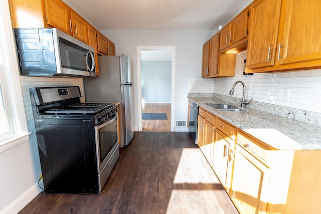 kitchen with sink, appliances with stainless steel finishes, dark hardwood / wood-style floors, tasteful backsplash, and light stone countertops