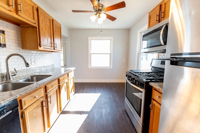 kitchen with appliances with stainless steel finishes, dark hardwood / wood-style floors, sink, decorative backsplash, and light stone counters