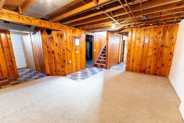 basement featuring carpet flooring and wood walls