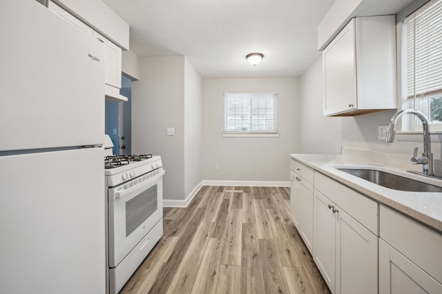 kitchen featuring sink, light wood-type flooring, white cabinets, plenty of natural light, and white appliances