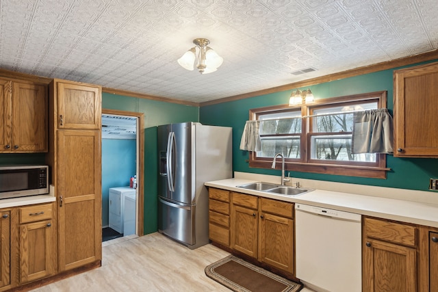 kitchen featuring crown molding, appliances with stainless steel finishes, sink, and separate washer and dryer