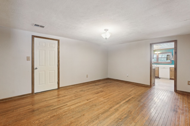 spare room featuring light hardwood / wood-style floors and a textured ceiling