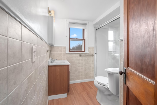 bathroom featuring walk in shower, toilet, tile walls, vanity, and hardwood / wood-style floors