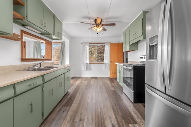 kitchen with appliances with stainless steel finishes, dark hardwood / wood-style floors, sink, ceiling fan, and green cabinetry