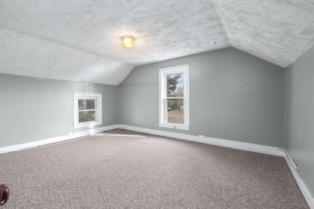 bonus room featuring lofted ceiling, carpet flooring, and a textured ceiling