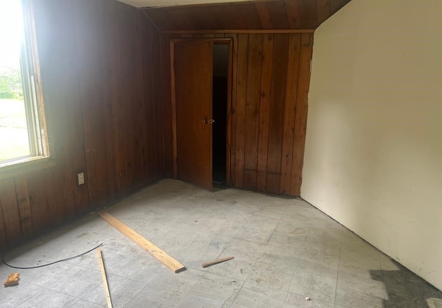 unfurnished room featuring wooden walls