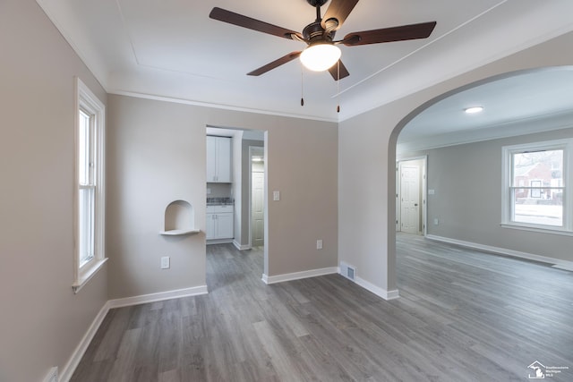 empty room with light hardwood / wood-style flooring, ornamental molding, and ceiling fan