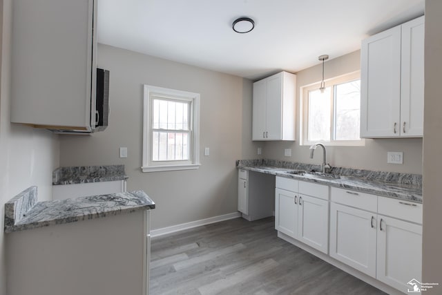 kitchen with a healthy amount of sunlight, sink, light hardwood / wood-style floors, and white cabinets