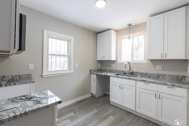 kitchen featuring white cabinetry, sink, decorative light fixtures, and a healthy amount of sunlight