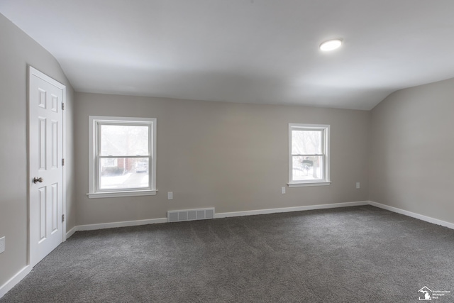 carpeted spare room featuring vaulted ceiling