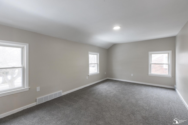 carpeted empty room featuring vaulted ceiling