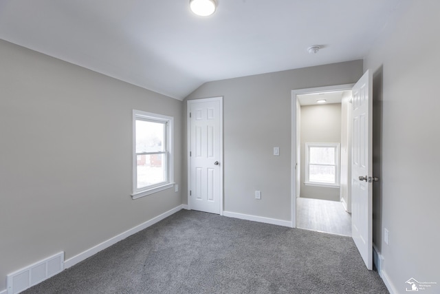 unfurnished bedroom featuring vaulted ceiling and carpet flooring