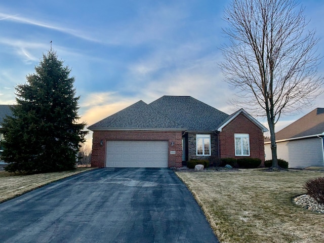 ranch-style house with brick siding, aphalt driveway, a front yard, roof with shingles, and a garage