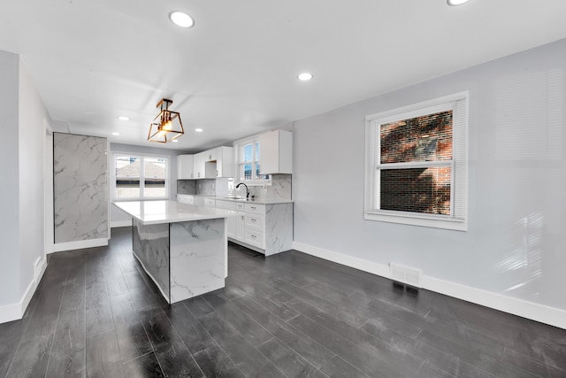 kitchen with white cabinetry, tasteful backsplash, decorative light fixtures, a center island, and dark hardwood / wood-style floors