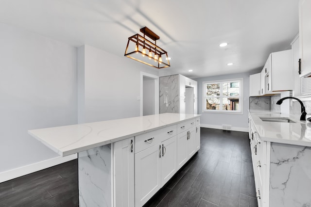 kitchen with a kitchen island, pendant lighting, sink, white cabinets, and dark wood-type flooring