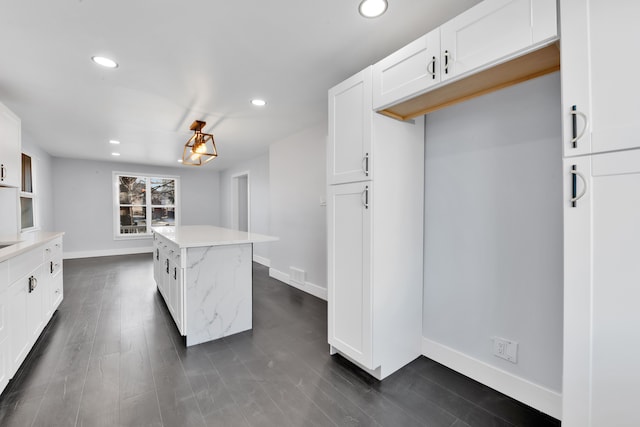 kitchen with white cabinetry, dark hardwood / wood-style floors, a center island, and light stone countertops