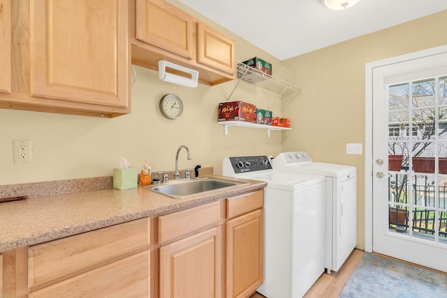 clothes washing area with washing machine and dryer, sink, a healthy amount of sunlight, and light hardwood / wood-style floors