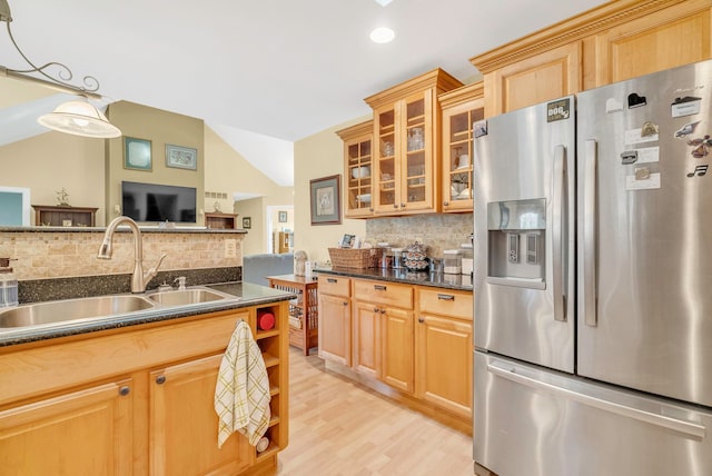 kitchen featuring lofted ceiling, sink, decorative light fixtures, stainless steel fridge, and backsplash