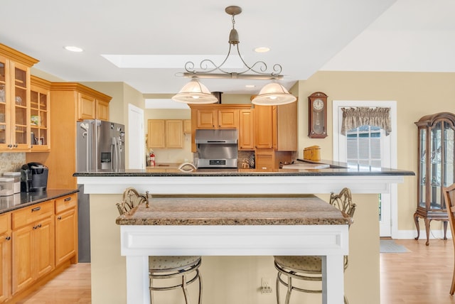 kitchen featuring decorative light fixtures, stainless steel fridge, a breakfast bar, and a kitchen island