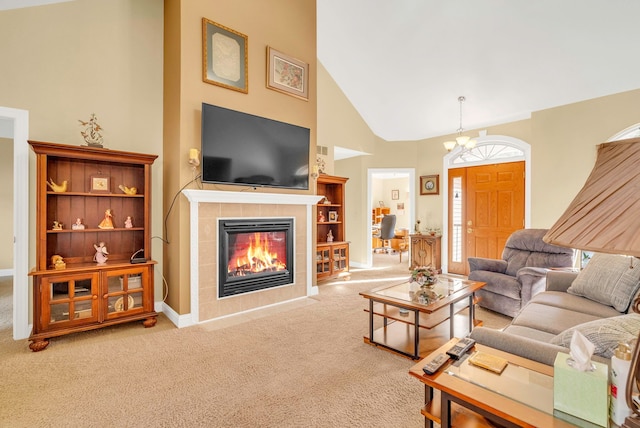 carpeted living room featuring a tiled fireplace, high vaulted ceiling, and an inviting chandelier