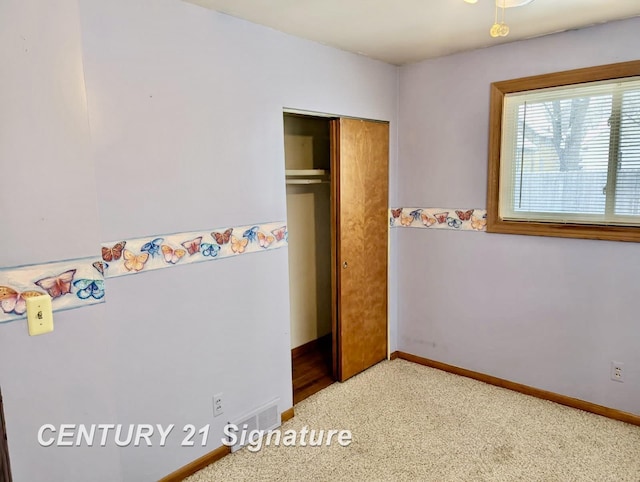 unfurnished bedroom featuring visible vents, baseboards, carpet, and a closet