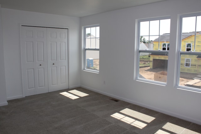 unfurnished bedroom with dark carpet and a closet