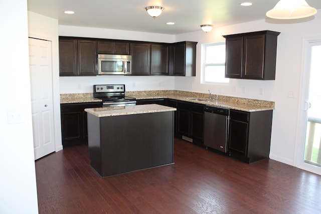 kitchen with dark brown cabinetry, dark wood-type flooring, a center island, and appliances with stainless steel finishes