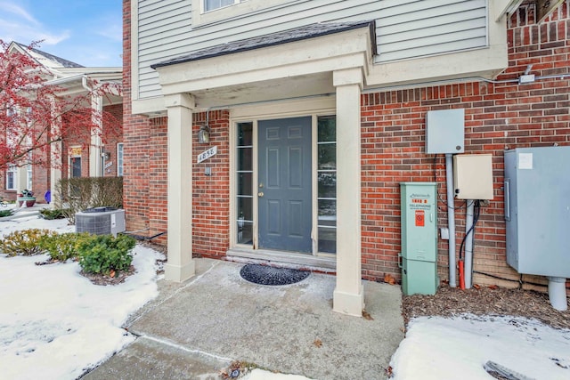 snow covered property entrance with central AC