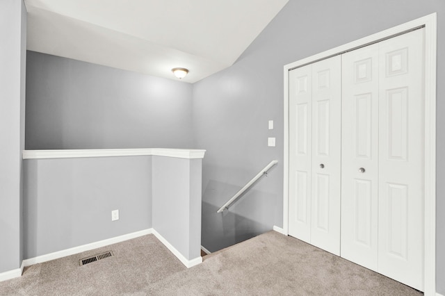 corridor with vaulted ceiling and carpet