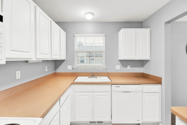 kitchen featuring white dishwasher, sink, and white cabinets