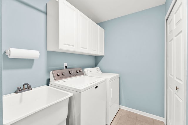 washroom featuring sink, light tile patterned floors, washer and clothes dryer, and cabinets