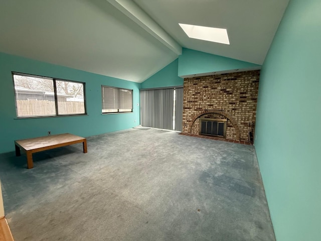 unfurnished living room with a brick fireplace, vaulted ceiling with skylight, and carpet flooring