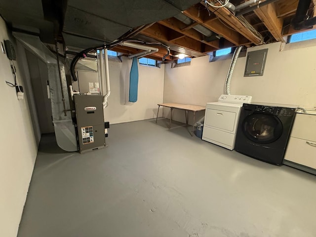 basement featuring washing machine and dryer, heating unit, and electric panel