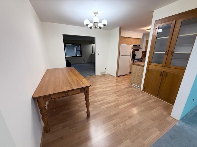 unfurnished dining area featuring a chandelier and light hardwood / wood-style flooring