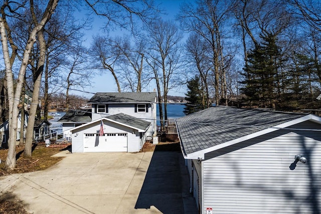 view of side of home with a detached garage and roof with shingles