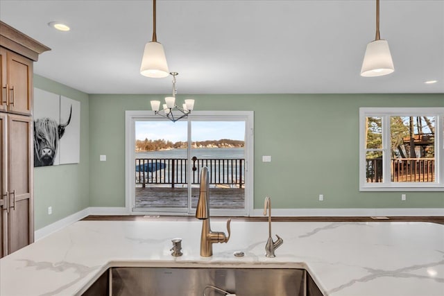 kitchen with a sink, decorative light fixtures, plenty of natural light, and an inviting chandelier